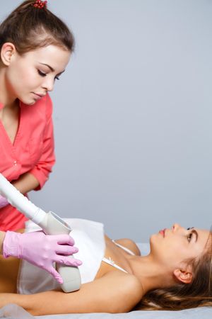 Cosmetologist doing beauty treatment on client’s arm, vertical composition