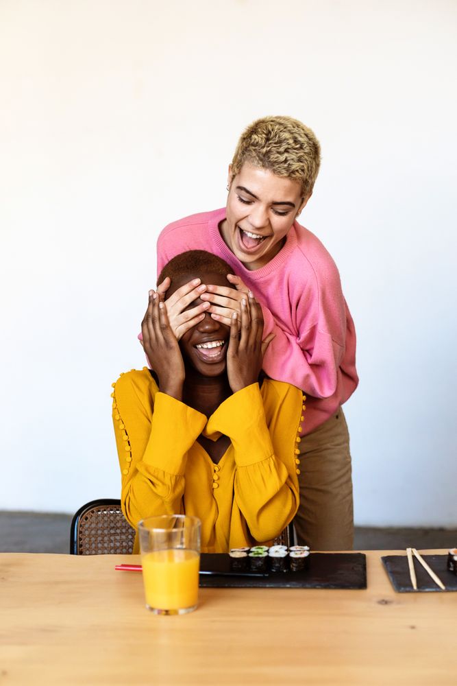 Female couple sharing surprise sushi at home