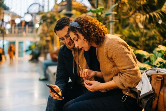 Couple using smartphone together on bench
