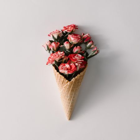 Ice cream cone with colorful flowers on light background