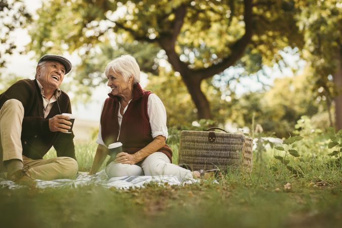Portrait of beautiful older couple sitting on blanket outdoor enjoying time together