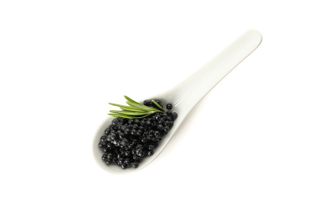 Glass spoon with caviar isolated on blank background