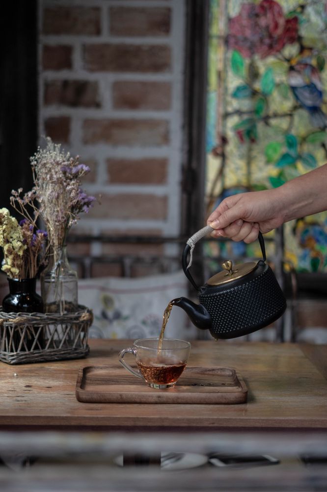 Person pouring cup of tea on table