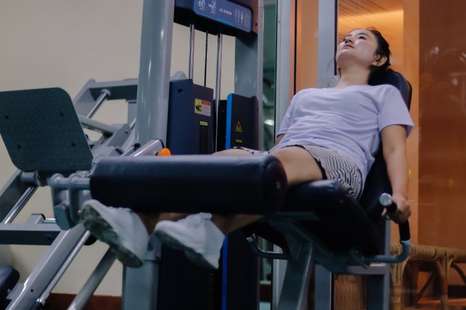 woman using leg extension machine inside the gym.