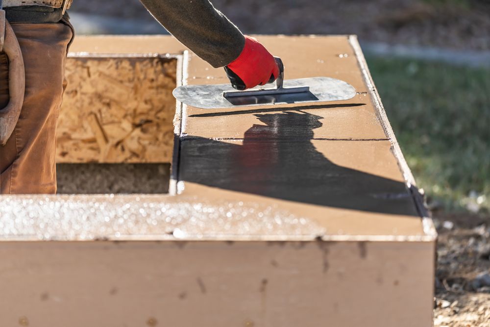 Construction Worker Using Trowel On Wet Cement Forming Coping Around New Pool