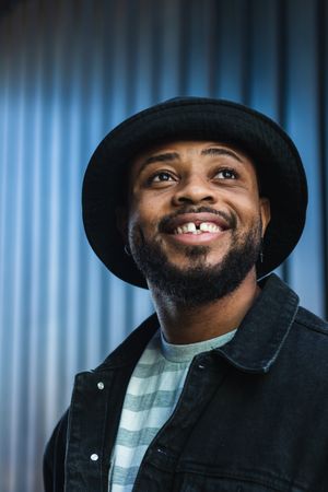 Smiling Black hipster man in hat looking up