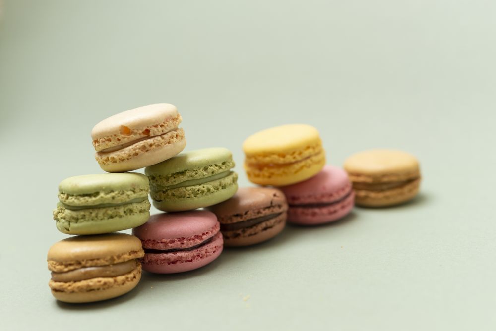 Pile of sweet pastel macaroons over a green background, with space for text