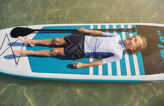Happy child resting on surfboard in ocean