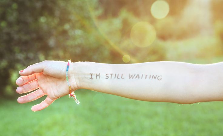 Female arm with text -I'm still waiting- written on skin