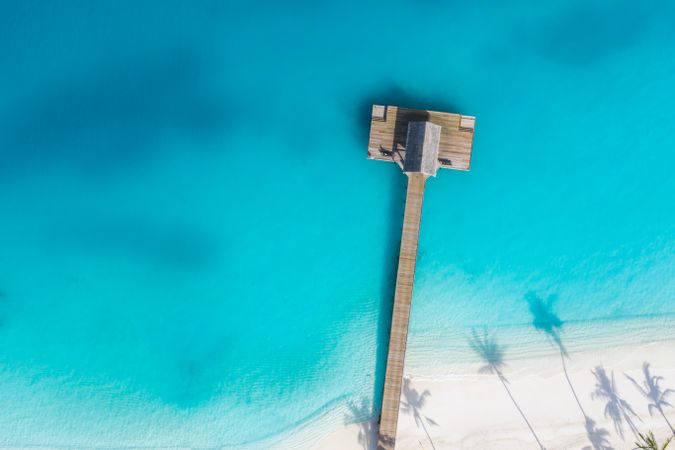 Aerial view of wooden pier on a tropical beach with clear water