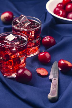 Red beverage near fresh fruits on cloth
