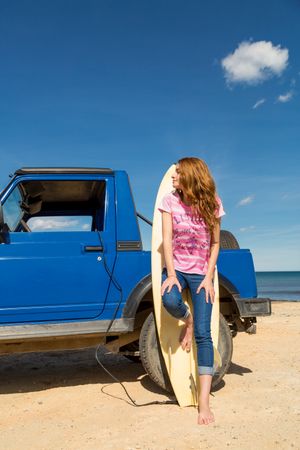 Woman leaning on surfboard near car at seaside