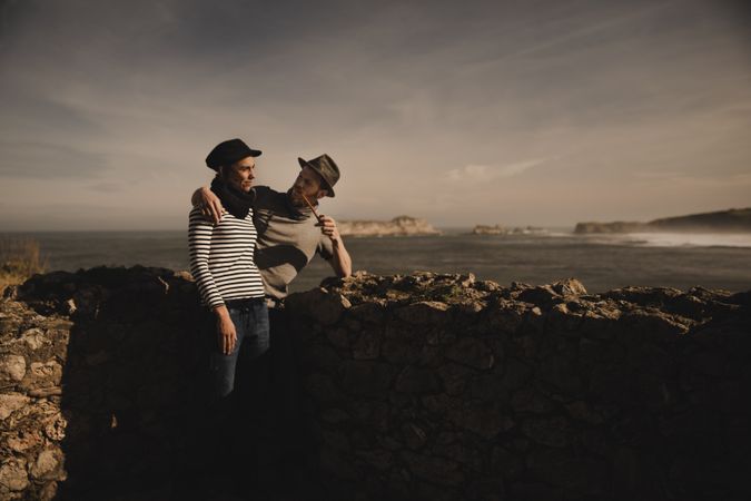 Man holding woman on hands near stones on shore