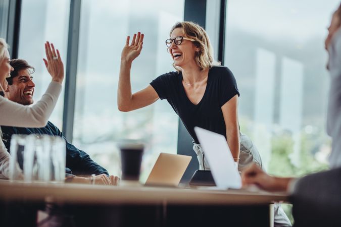 Female CEO giving high five to woman at conference table