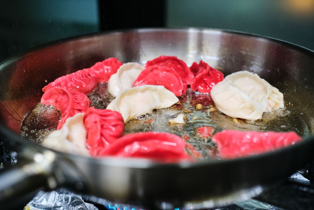 Colorful jiaozi frying in pan on stove
