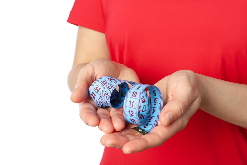Woman holds measuring tape, isolated on blank background. Healthy lifestyle