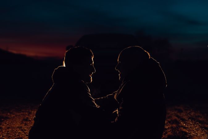 Men hugging and sitting on ground on field at night