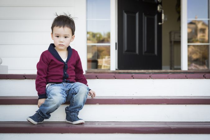 Young Boy Sitting on Front Porch Steps