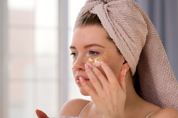 Applying eye patches in skincare routine.