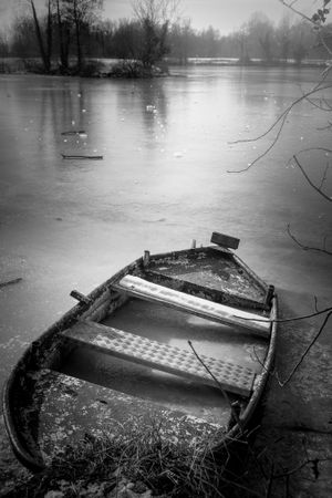 Boat frozen in ice on lake, monochrome