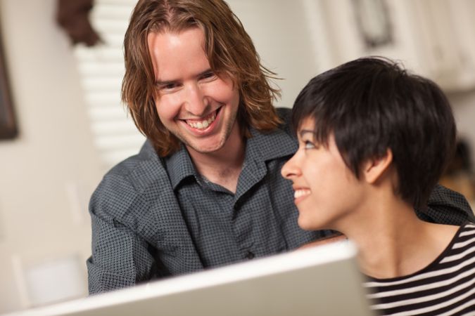 Happy Young Man and Woman Using Laptop Together