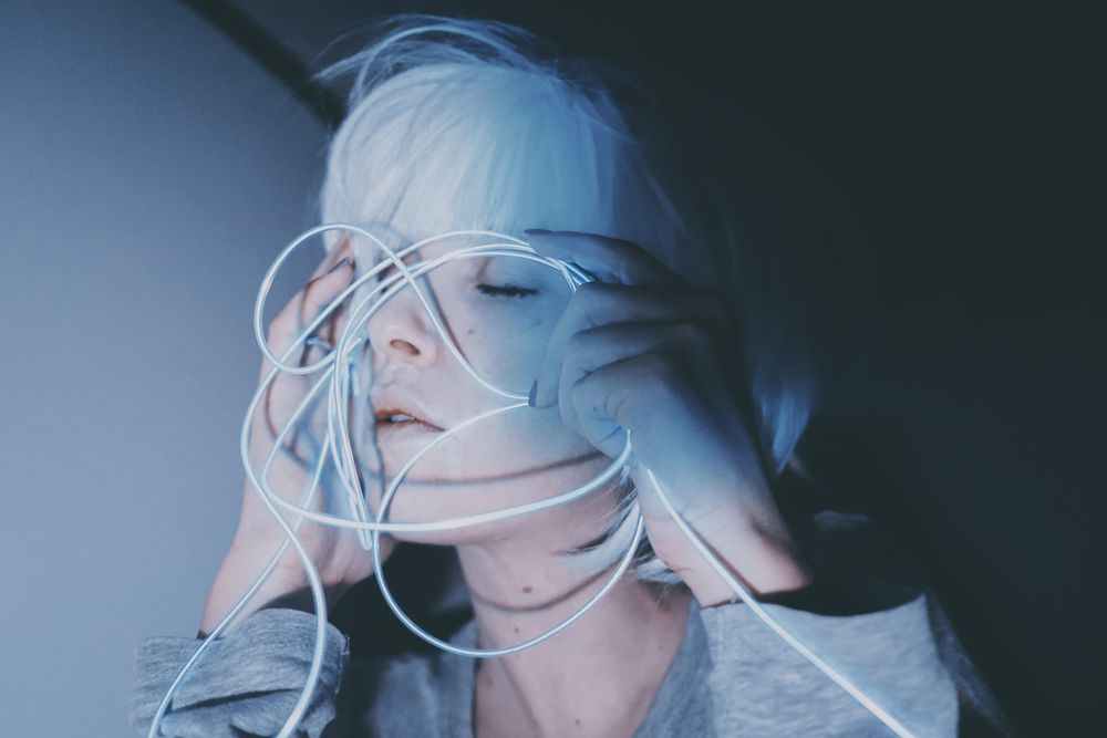 Portrait of woman with light hair holding blue led light thread closing her eyes