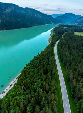 Drone shot in Bavarian Alps with Lake Sylventein and road through the forest
