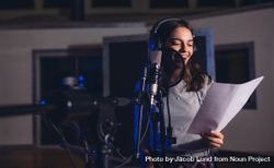 Smiling female singer with microphone and reading lyrics 4MxBq5