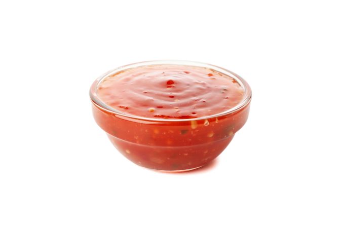 Bowl with tasty chilli sauce isolated on plain background