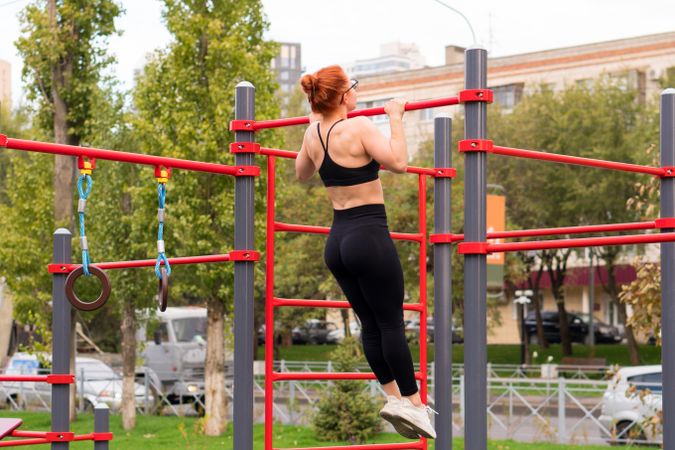 Woman practicing pull-ups on red fitness structure