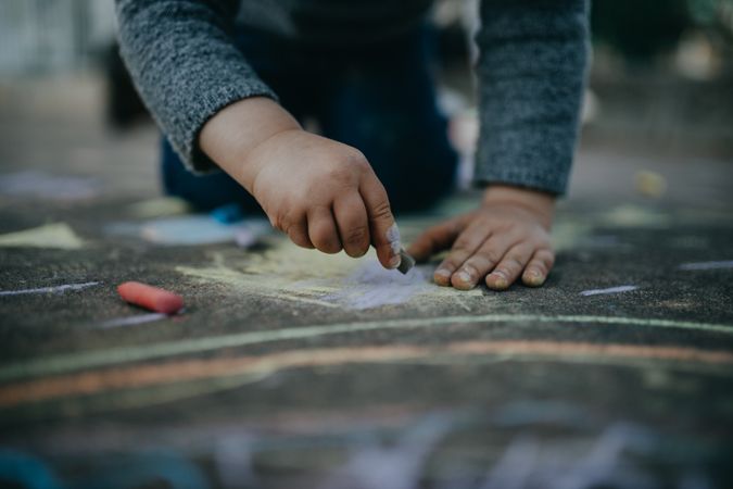 Child drawing with chalk on the pavement outside