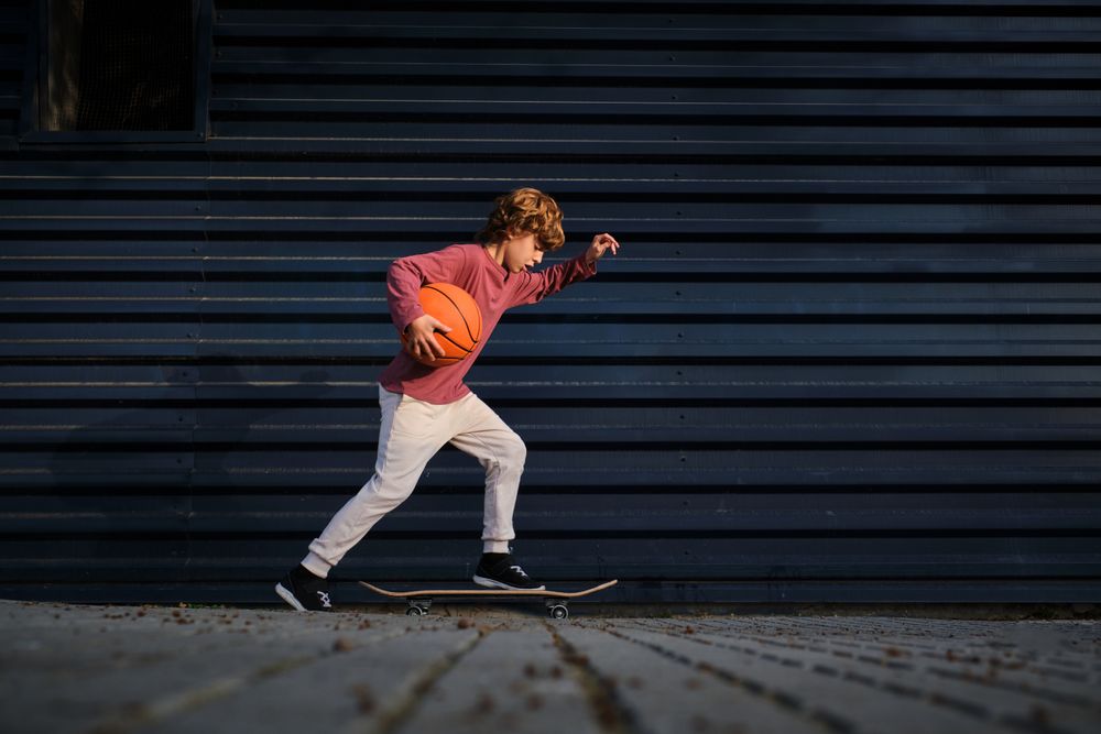 Little basketball player riding skateboard