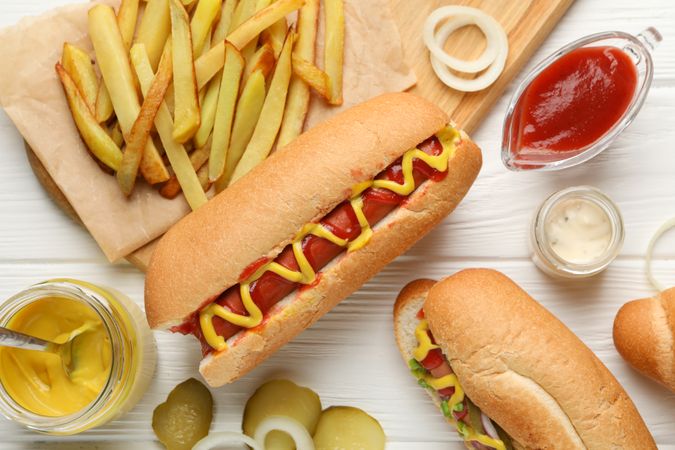 Hot dogs, fries potato and sauces on plain wooden background