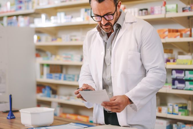 Male pharmacist reading prescription at checkout counter
