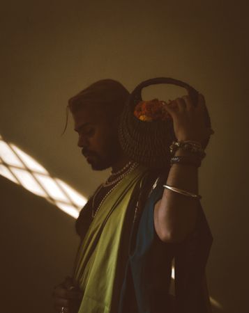 Side view of a man holding a basket of fruit in dark room