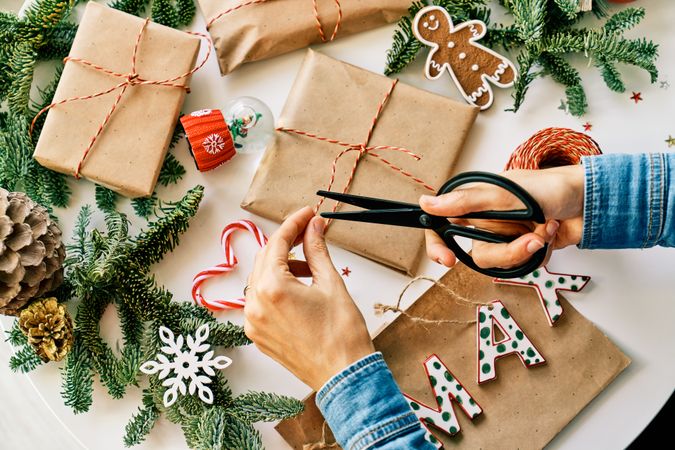Faceless person wrapping Christmas presents on table