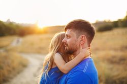 Man carrying daughter in long grass meadow at meadow