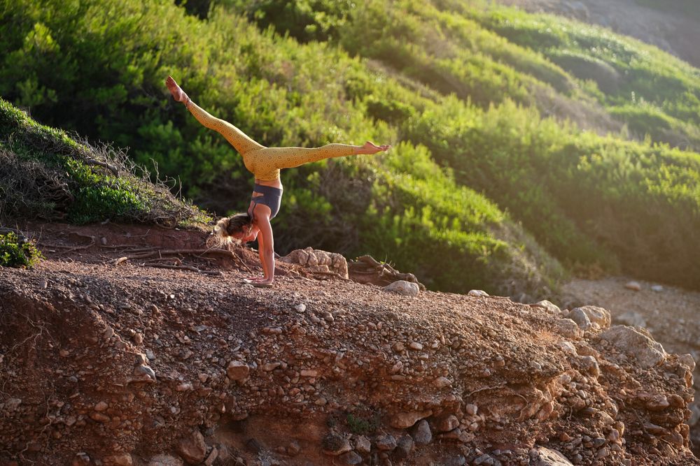 Anonymous female athlete practicing yoga in handstand in nature