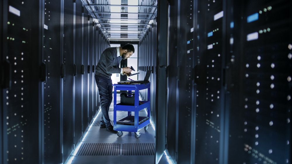 IT Engineer Works on a Laptop and Scans Hard Drives That are Lying on a Crash Cart.