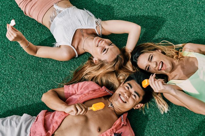 a group of young people having a good time and eating ice-cream lying on grass