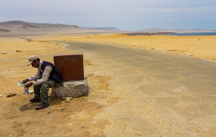 Peru - January, 02 2012: Man reading newspaper near countryside road