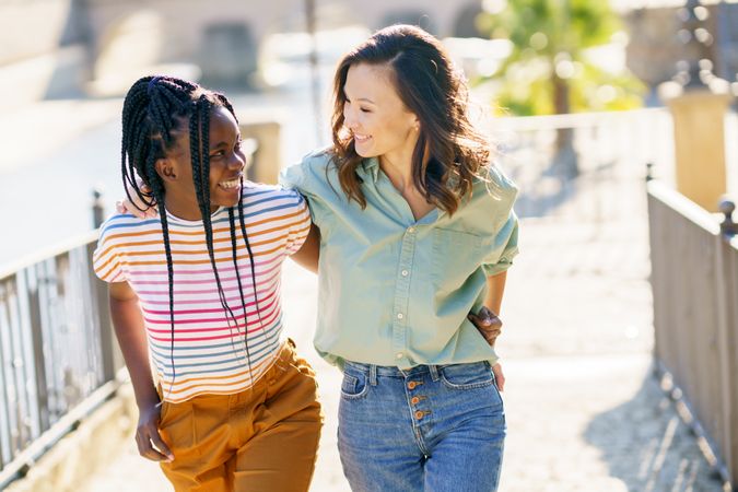 Female friends smiling in casual clothing walking up cobble stone path