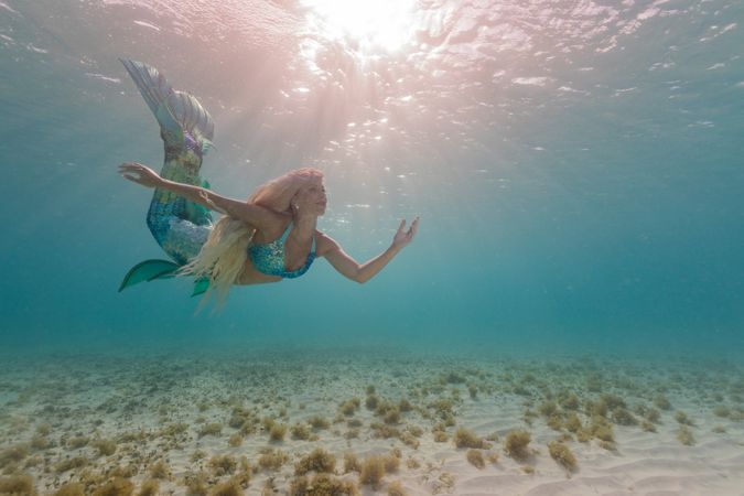 Blond fairytale female mermaid swimming underwater