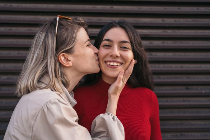 Female friends kissing on the cheek. Blonde and brunette