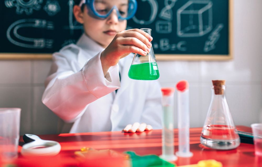 Serious boy holding flask with green liquid