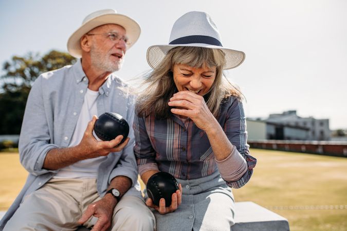 Older woman in hat laughing while sitting in a park with her friend