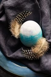 Easter holiday table setting with close up of Easter egg & feather