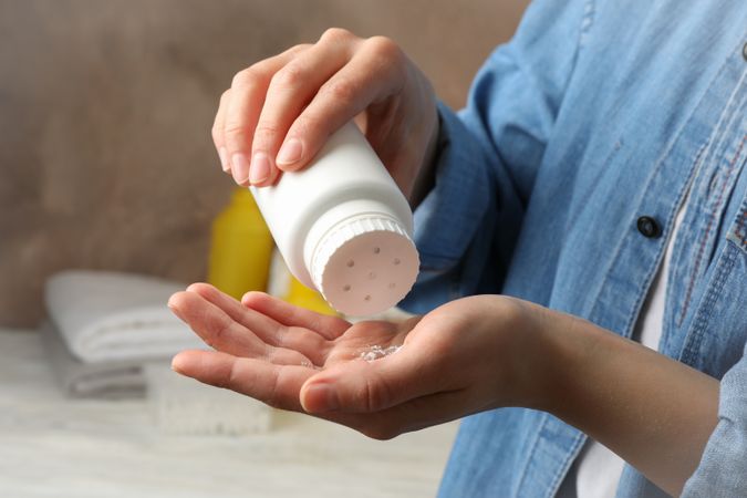 Mom applying talc powder from plastic tube. Baby hygiene
