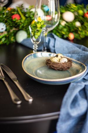 Easter table setting with nest and eggs on ceramic plate