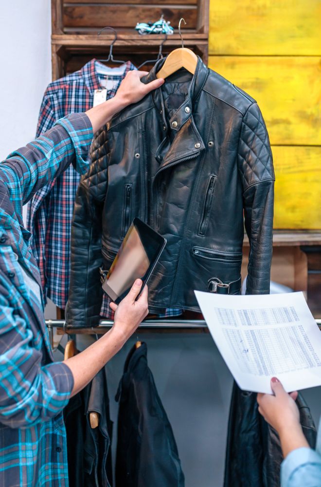 Unrecognizable woman entrepreneur holding leather jacket on local shop
